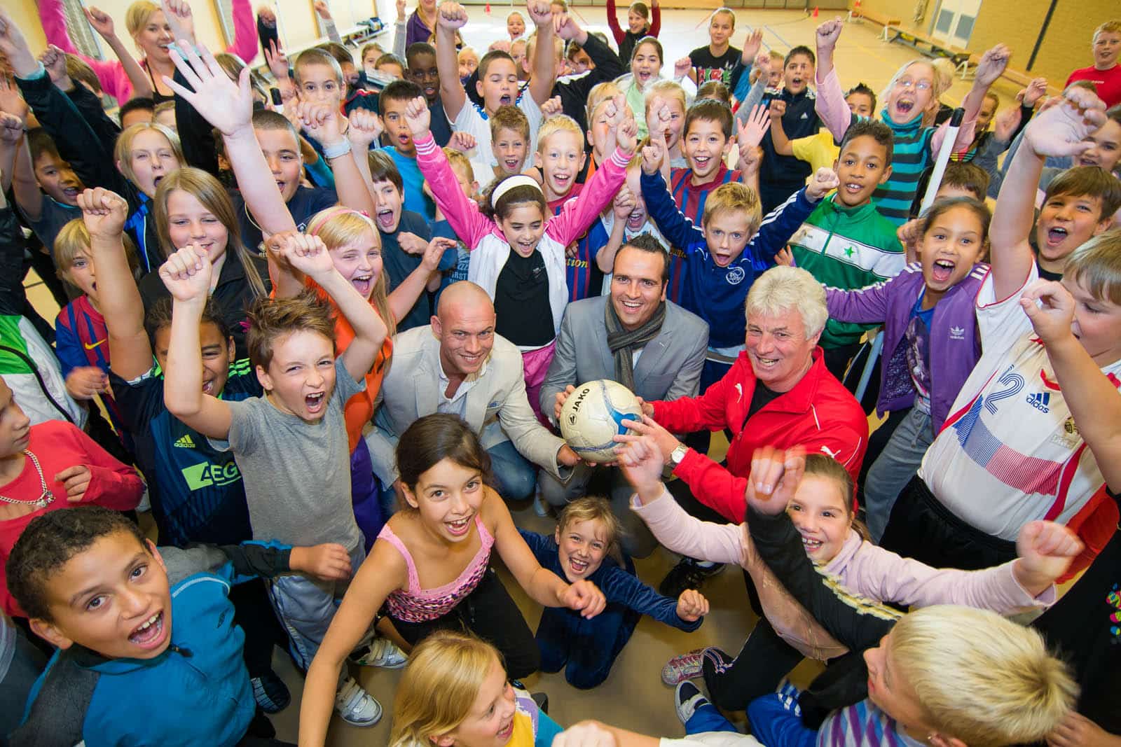Juichende schoolkinderen rond een sporter tijdens Active Living van de gemeente Brunssum Juichende schoolkinderen rond een sporter tijdens Active Living van de gemeente Brunssum