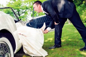 Bruidsfotograaf Limburg - De bruidegom gaat de voeten van de bruid kussen. Ze zit lekker in de oldtimer