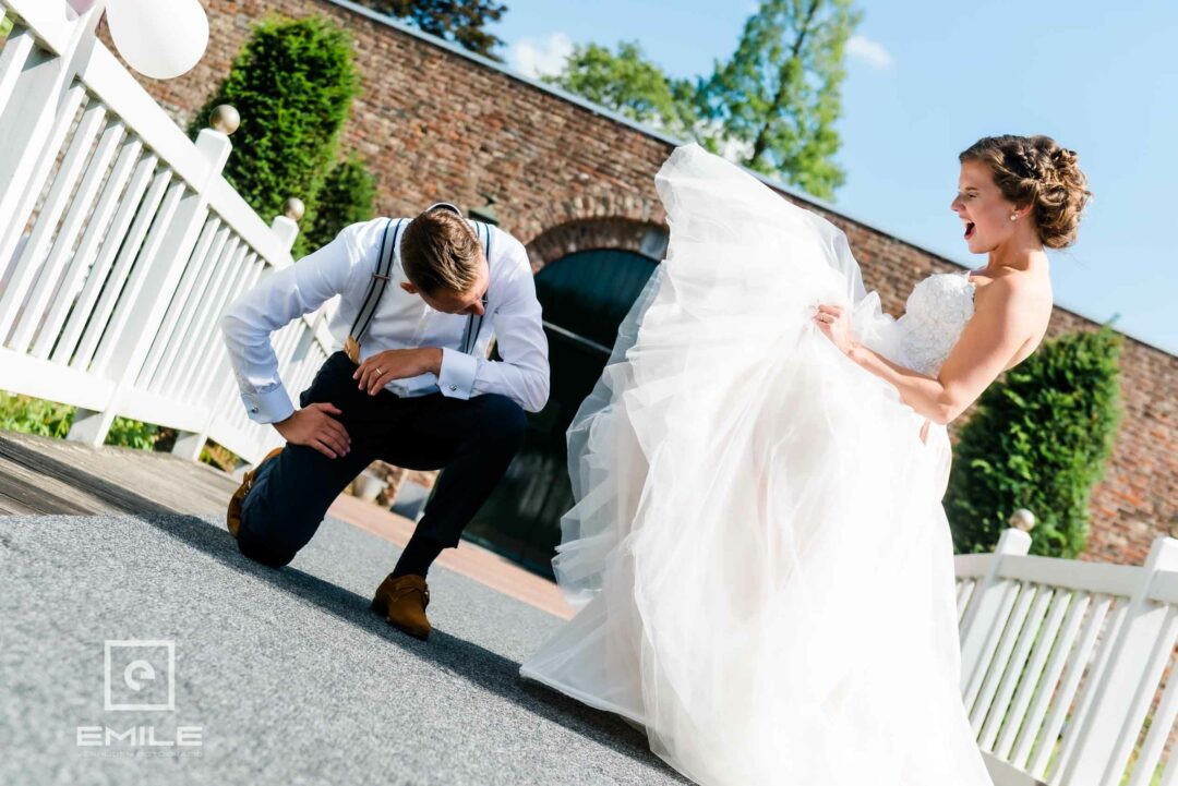 De bruidegom gooide tijdens de fotoshoot haar rok omhoog. Het was een komisch en onvergetelijk moment op hun trouwdag, en het bruidspaar zou later nog vaak terugdenken aan dit vreemde, maar leuke voorval. Bruidsfotograaf Limburg - Kasteel Daelenbroeck - Herkenbosch