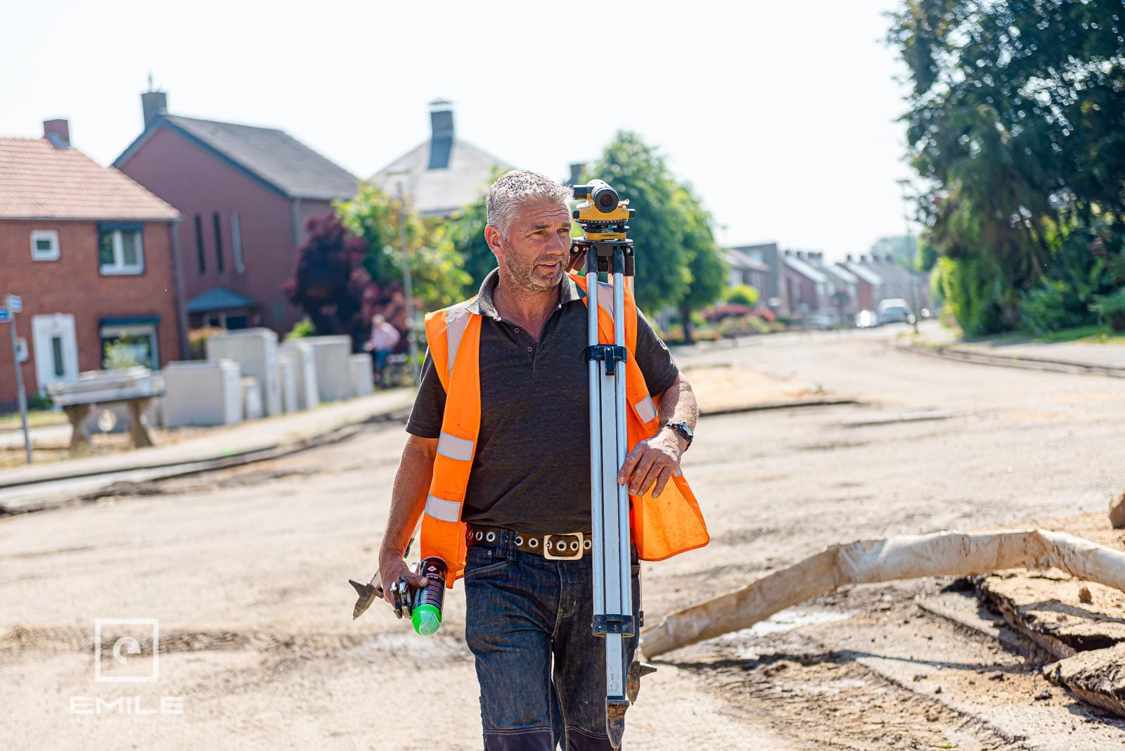Landmeter met meetapparatuur loopt over een straat in aanleg Landmeter met meetapparatuur loopt over een straat in aanleg