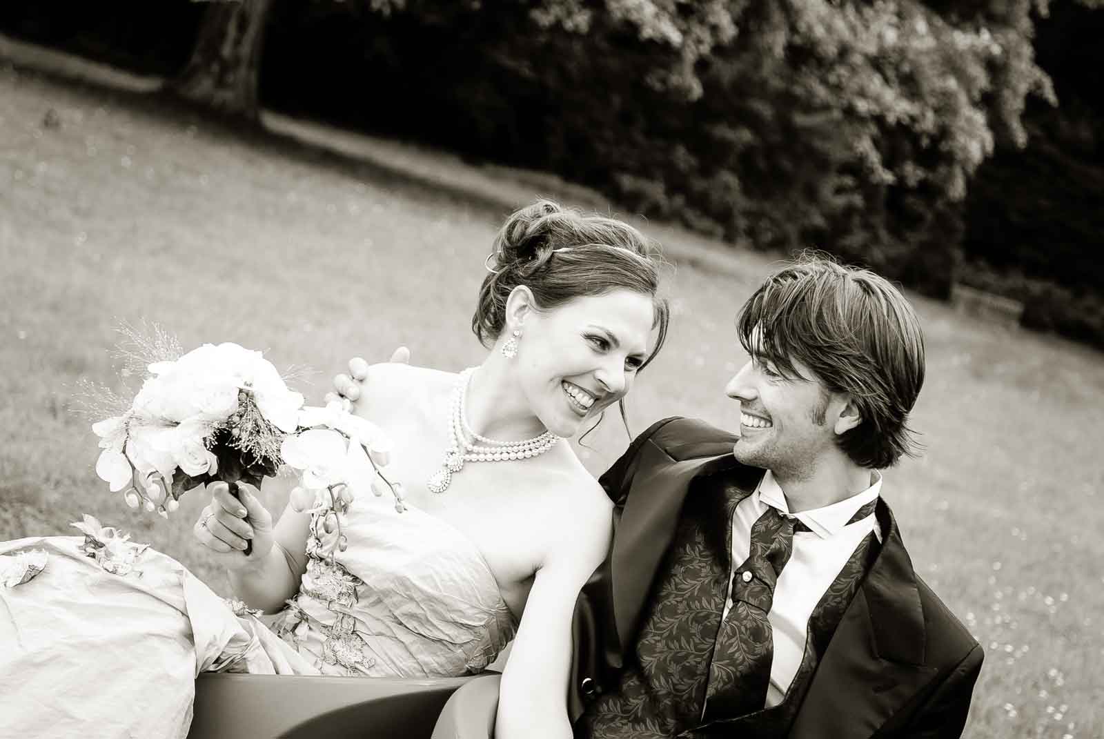 Huwelijk in de tuin van Kasteel Vaeshartelt te Maastricht. Bruidspaar kijkt lachend naar elkaar zitten op 2 stoeltjes