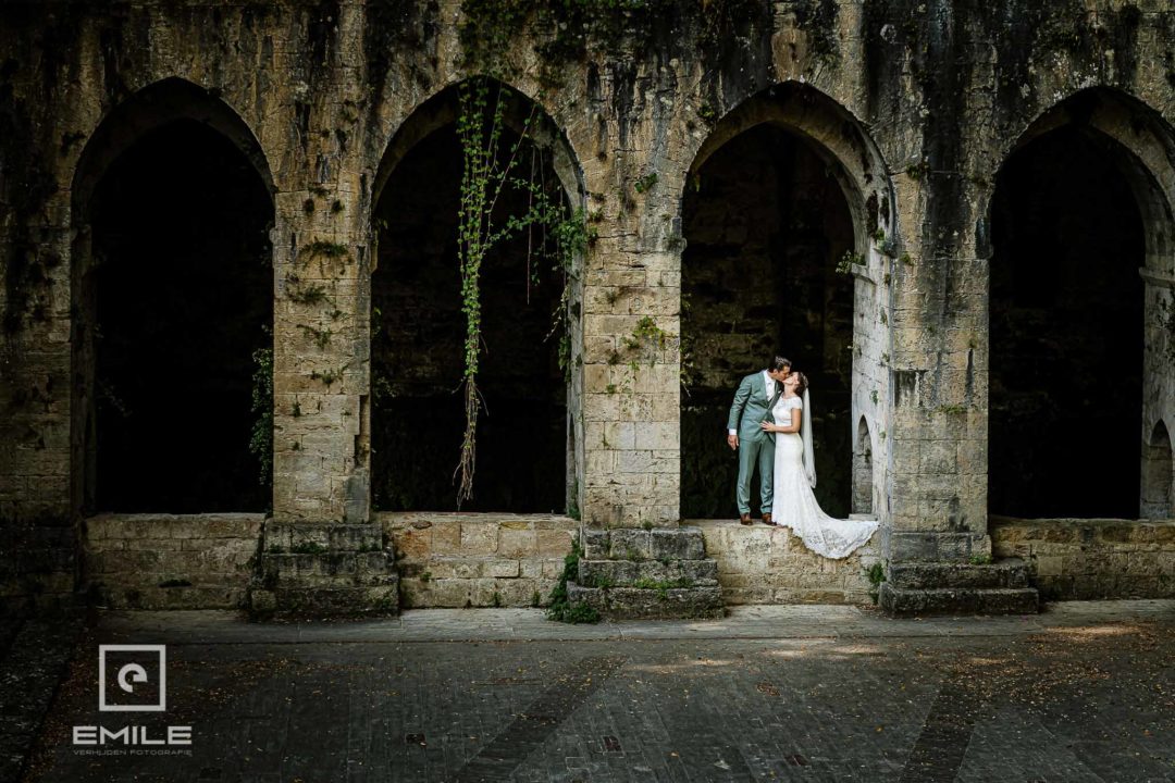 Bruidspaar bij de ruine van Poggibonsi geven elkaar een kus staand tussen 2 pilaren - Destination wedding San Gimignano - Toscane Italie - Iris en Job
