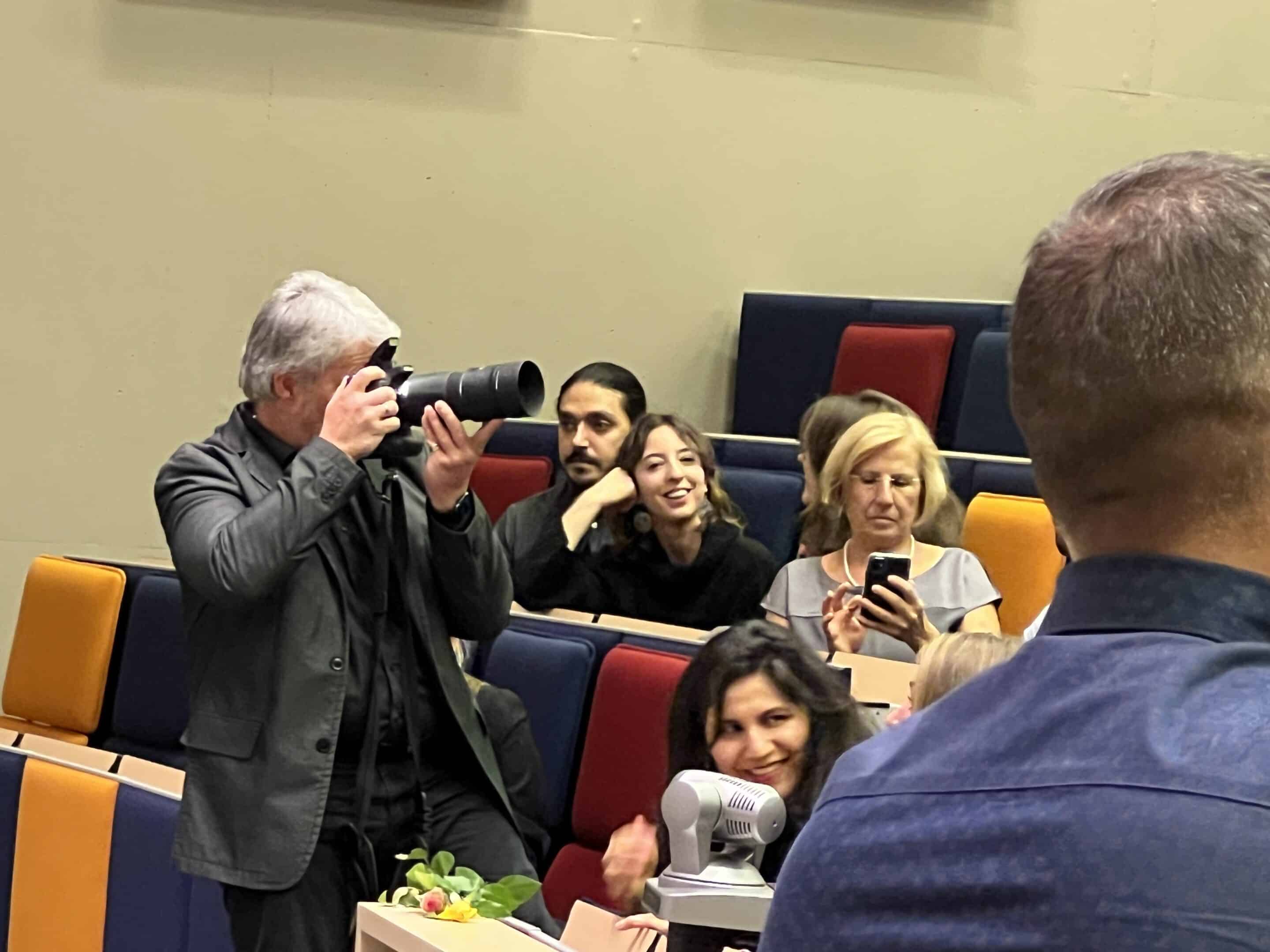 Fotograaf met een telelens en een flitser in een volle zaal Fotograaf met een telelens en een flitser in een volle zaal
