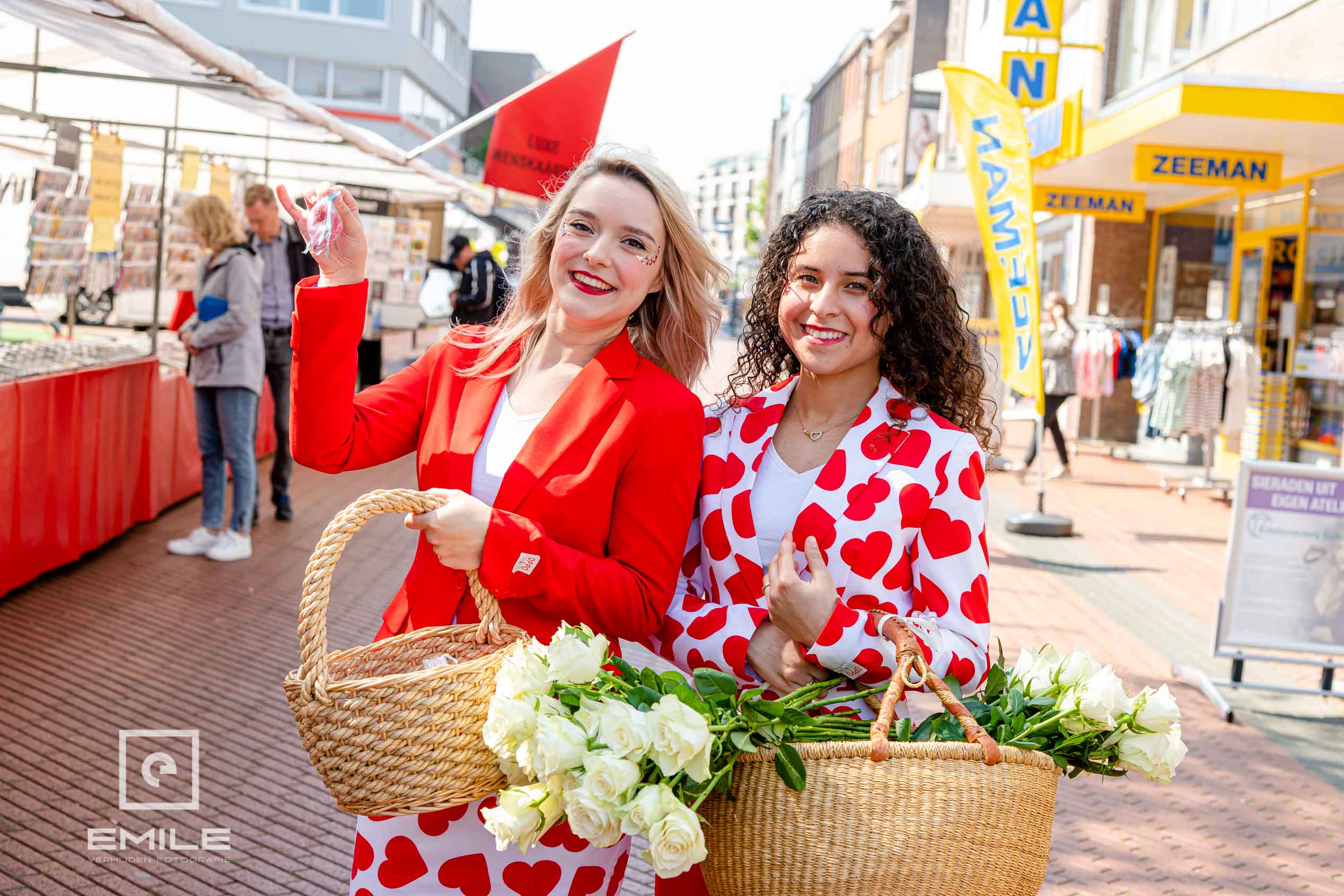 Twee vrouwen met bloemenmanden in de winkelstraat van Brunssum tijdens een campagne voor Moederdag Twee vrouwen met bloemenmanden in de winkelstraat van Brunssum tijdens een campagne voor Moederdag
